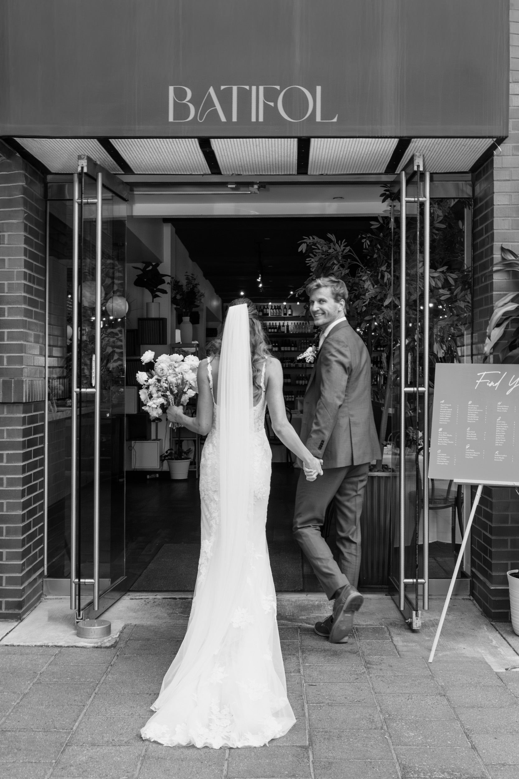 Black and white photo of bride and groom entering Batifol restaurant after ceremony Cambridge MA wedding