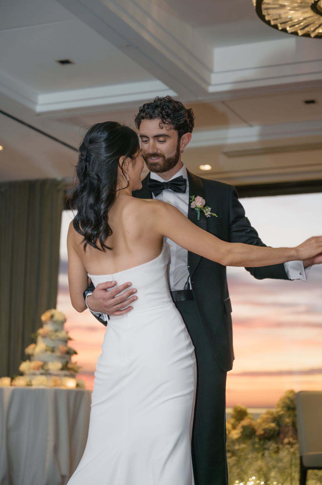 Bride and groom ending their first dance with a dip as the Boston sunset fills the floor-to-ceiling windows at UMass Club Boston